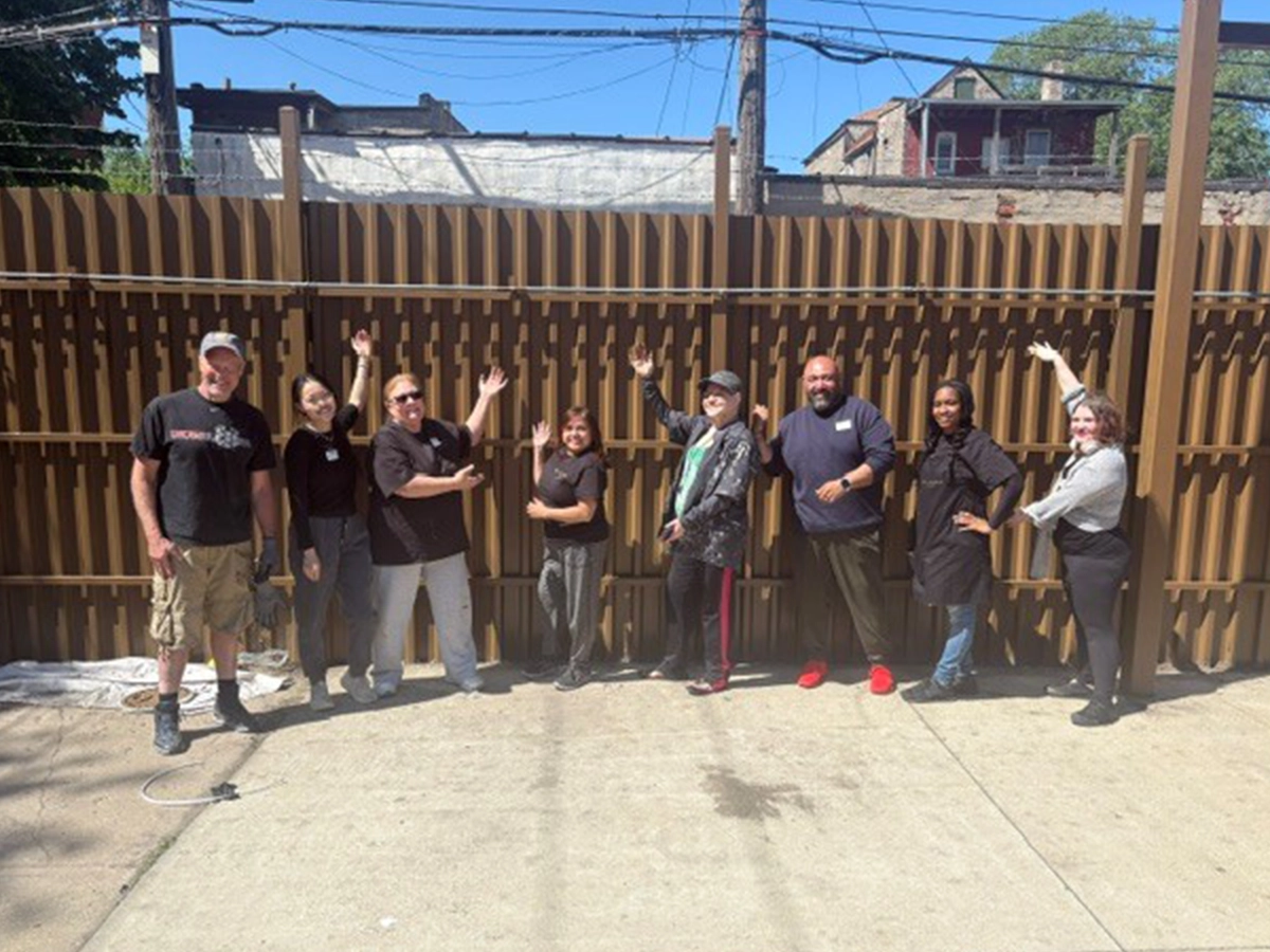 Volunteers painting the Covenant House courtyard fence